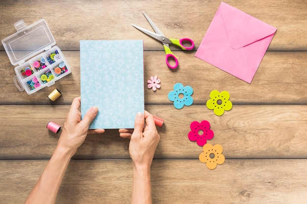 Close-up of hand making greeting card on wooden plank