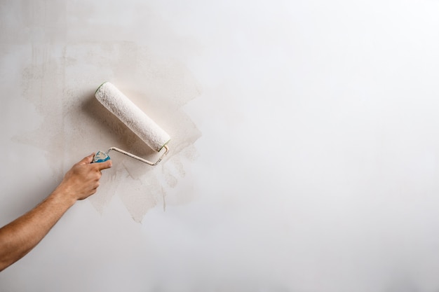 Close up of hand painting wall with roller.