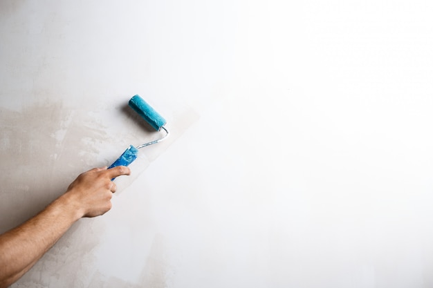 Close up of hand painting wall with roller.