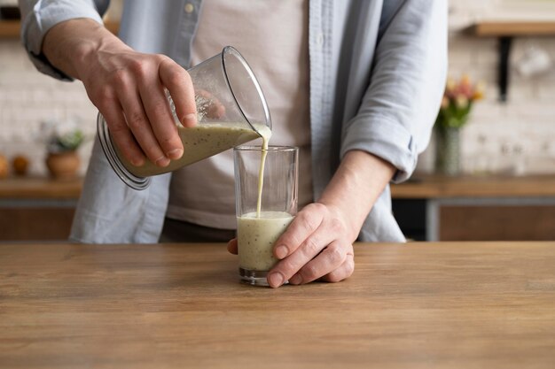 Close up hand pouring smoothie in glass