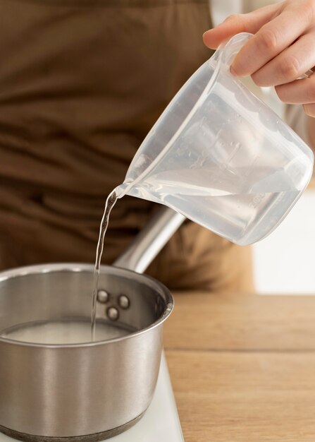 鍋に水を注ぐ手をクローズアップ