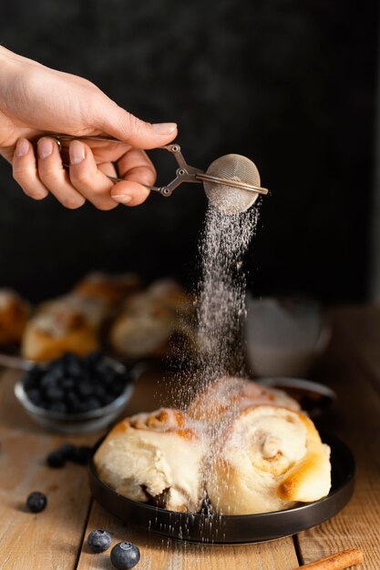 Close up hand powdering cinnamon roll