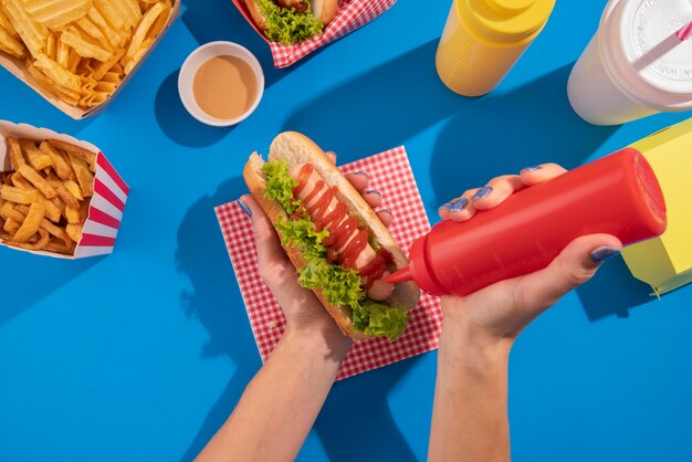 Close up hand putting ketchup on hot dog