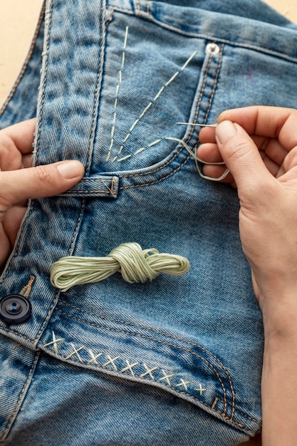 Close-up hand sewing jeans