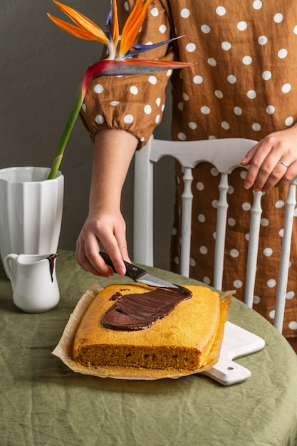 Foto gratuita close-up mano diffusione di cioccolato sulla torta