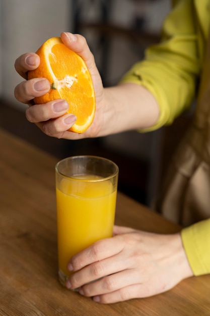 무료 사진 주스를 위해 오렌지를 짜내는 손을 닫습니다