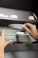 Free photo close-up of hand stacking white saucer in the shelf