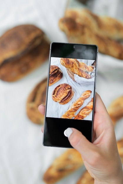 Chiuda sulla mano che prende le foto del pane