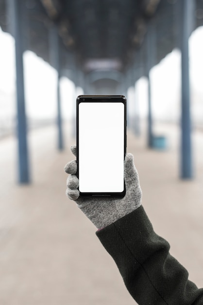 Close-up of hand wearing gloves showing smart phone with white screen