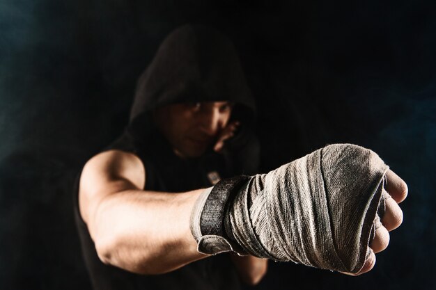 Крупным планом рука с повязкой мускулистого мужчины, тренирующего кикбоксинг на черном