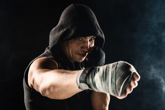 Close-up hand with bandage of muscular man training kickboxing  on black