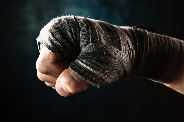 Close-up hand with bandage of muscular man training kickboxing  on black