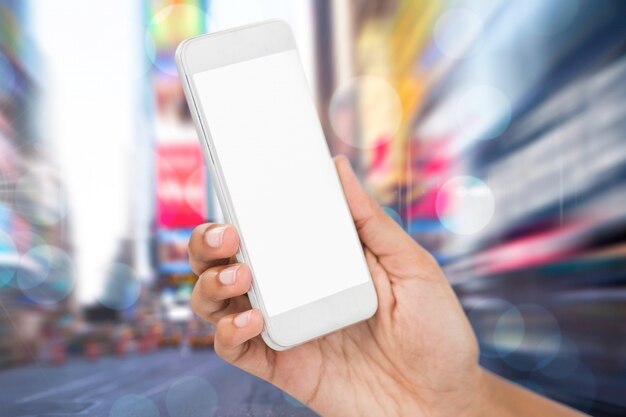 Close-up of hand with mobile phone over blurry cityscape