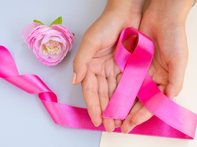 Close-up hand with pink ribbon and rose