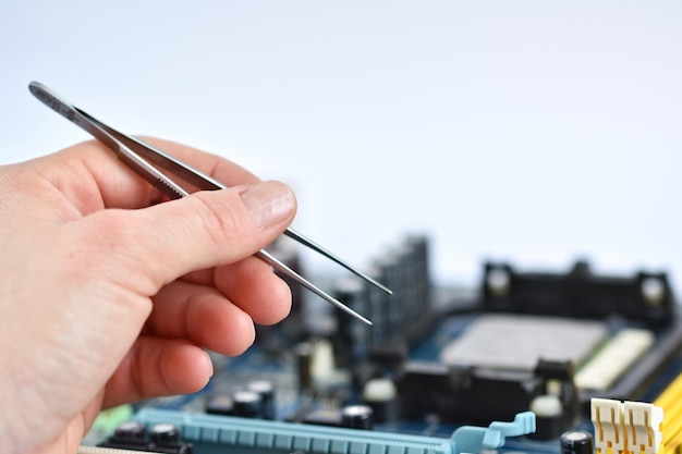 Close-up of hand with pliers to check a motherboard