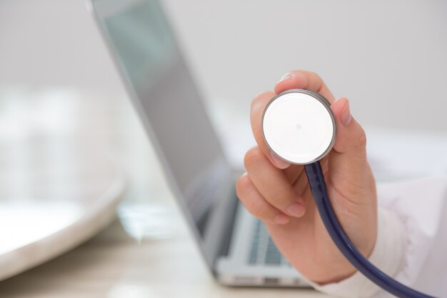 Close-up of hand with stethoscope and laptop background