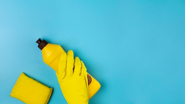 Close-up hand with yellow glove on blue background