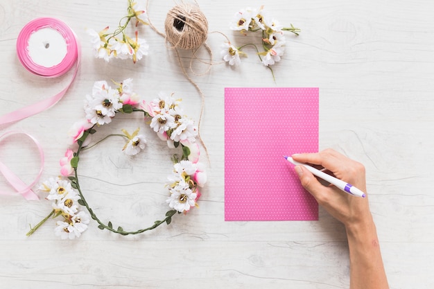 Close-up of hand writing message on scrapbook pink paper with decorative wreath