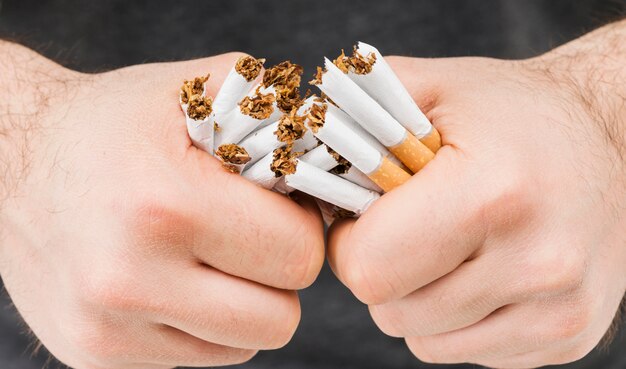 Close-up of hands breaking bundle of cigarettes