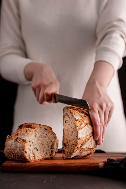 Close-up hands cutting bread with knife