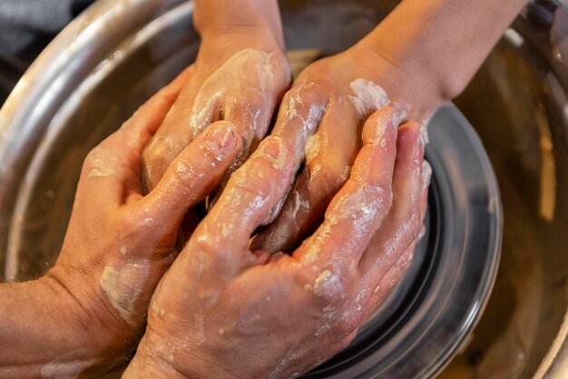 Close up hands doing pottery together