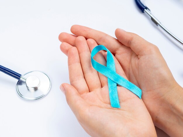 Close-up hands holding blue ribbon with stethoscope