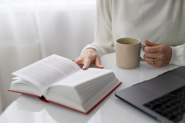 Close up hands holding book and cup