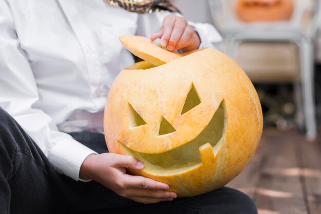 Close-up hands holding carved pumpkin