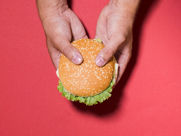 Foto gratuita mani del primo piano che tengono cheeseburger