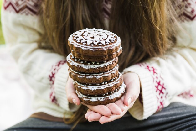 Крупный план рук, содержащих шоколадный печенье с дизайном обледенения