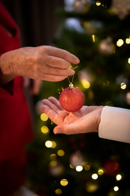 Foto gratuita mani del primo piano che tengono la palla di natale