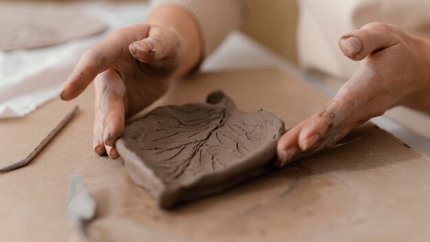 Close-up hands holding clay leaf