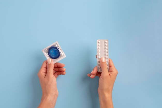 Close up hands holding condom and pills