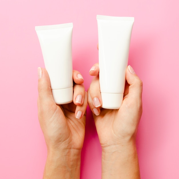 Close-up hands holding cream bottles