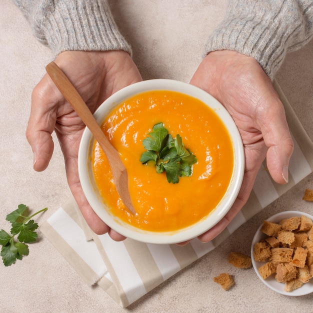 Free photo close-up hands holding cream soup bowl