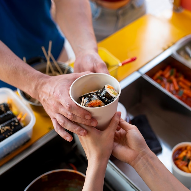 Close up hands holding cup with sushi