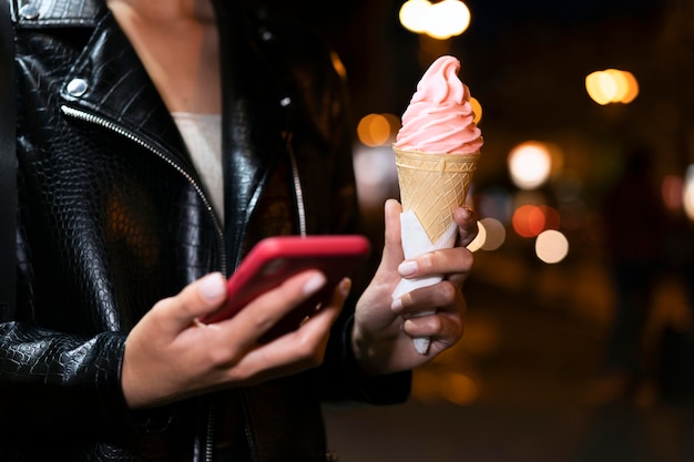 Close up hands holding ice cream and phone