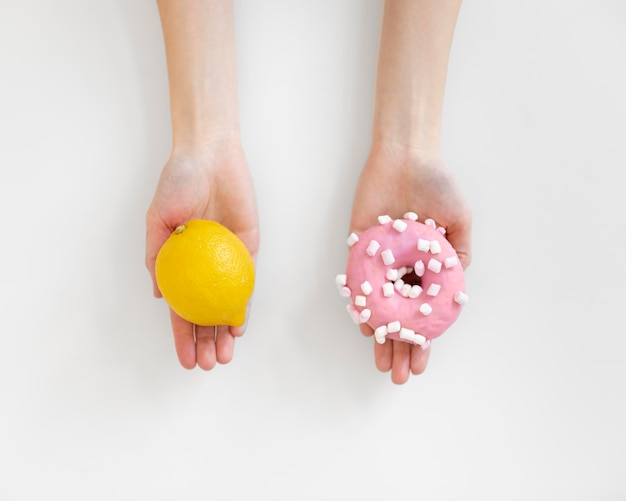 Close up hands holding lemon and doughnut