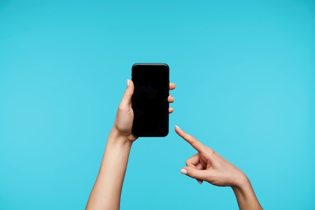 Close up on hands holding modern mobile phone and showing on black screen isolated