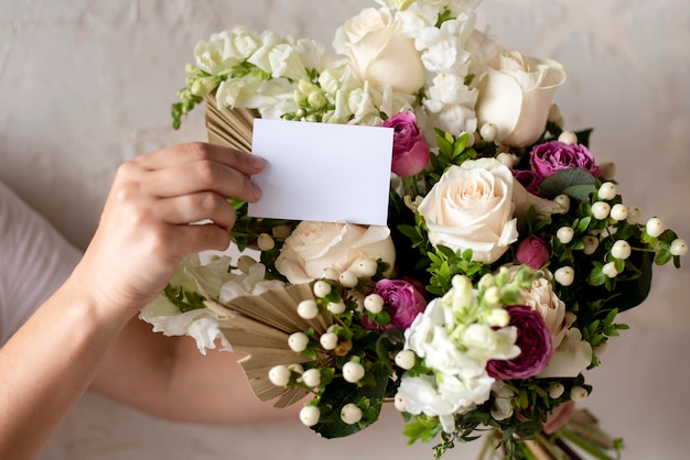 Foto gratuita mani ravvicinate che tengono nota e bouquet