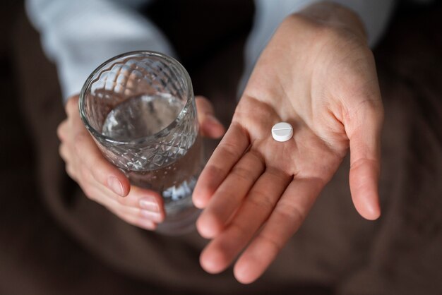 Close up hands holding pill and glass