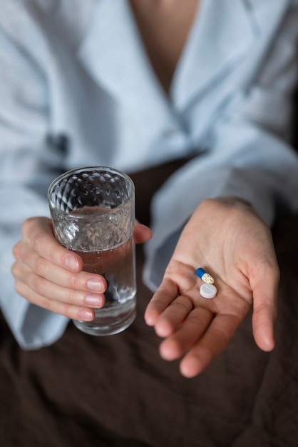 Close up hands holding pills and water