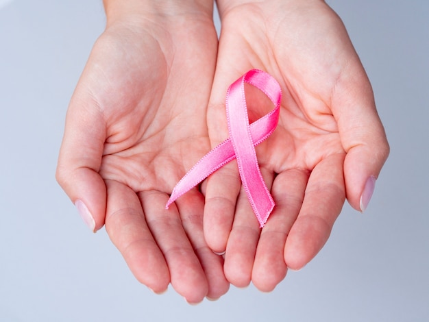 Close-up hands holding pink ribbon