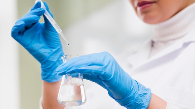 Close-up hands holding pipette and glass