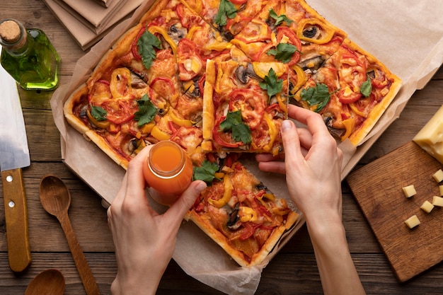 Foto gratuita mani ravvicinate che tengono pizza e drink