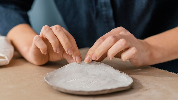 Mani del primo piano che tengono oggetto di ceramica