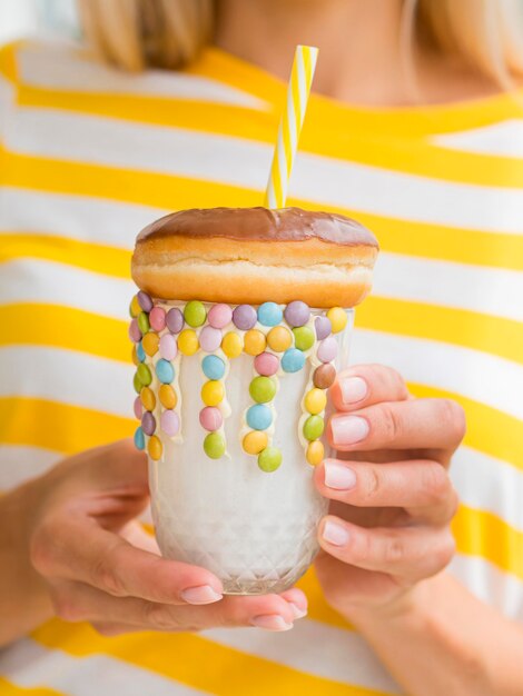 Close-up hands holding shake with doughnut