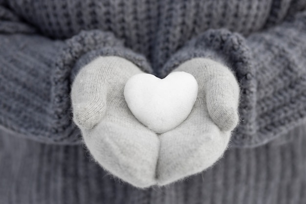 Close up hands holding snow heart