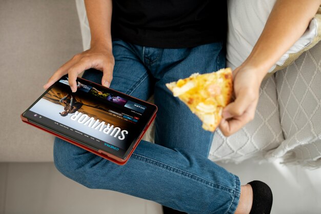 Close up hands holding tablet and pizza