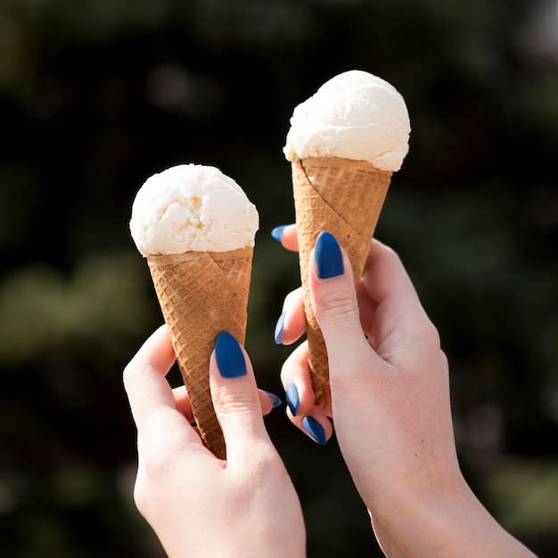 Foto gratuita mani del primo piano che tengono gustosi gelati